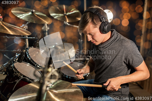 Image of musician playing drum kit at concert over lights