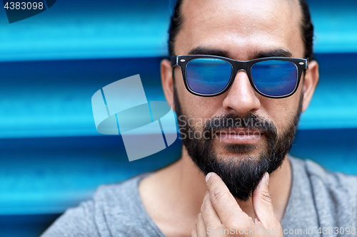 Image of close up of man in sunglasses touching beard