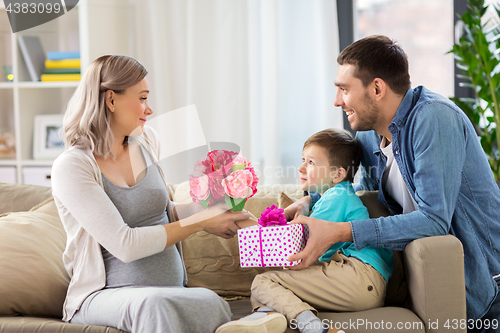 Image of family giving present to pregnant mother at home