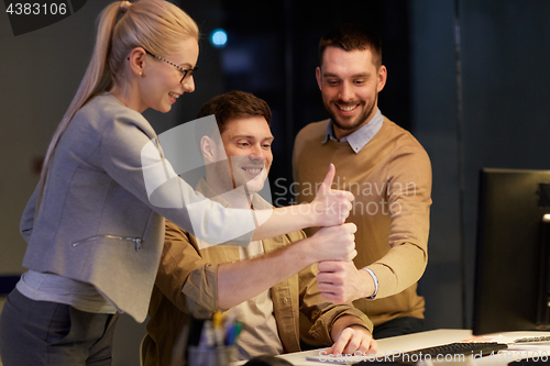 Image of business team making thumbs up gesture at office