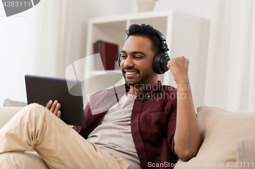 Image of man in phones with tablet pc listening to music