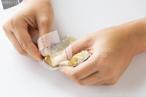 Image of woman hands opening pack of medicine capsules