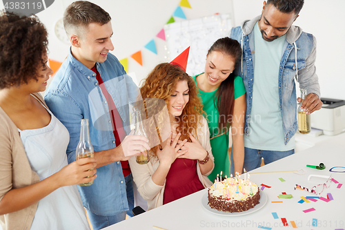 Image of happy coworkers with cake at office birthday party