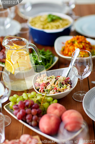 Image of salad, jug of water and other food on wooden table