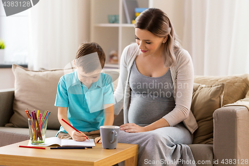 Image of pregnant mother and son with workbook at home