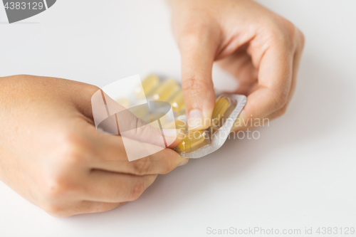 Image of woman hands opening pack of medicine capsules