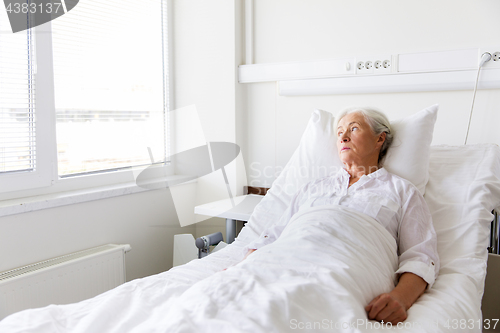 Image of sad senior woman lying on bed at hospital ward