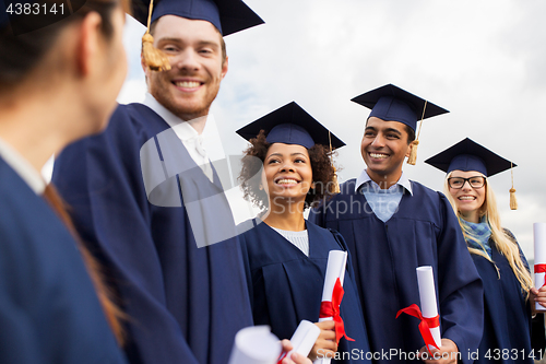 Image of happy students in mortar boards with diplomas