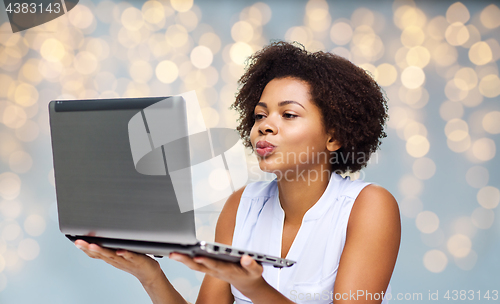 Image of woman with laptop computer sending kiss to someone