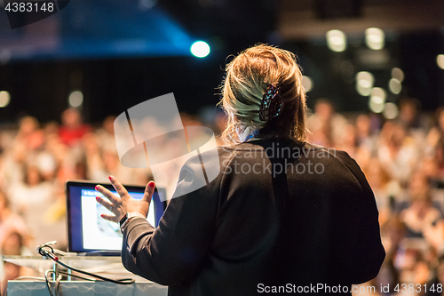 Image of Female public speaker giving talk at Business Event.