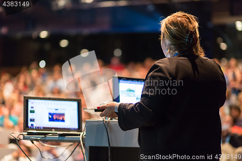 Image of Female public speaker giving talk at Business Event.