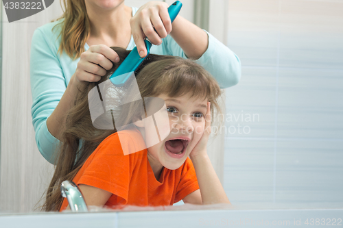 Image of Mom and daughter are having fun while mum combing the childs hair