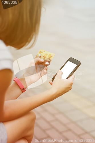 Image of Woman using phone and card for shopping