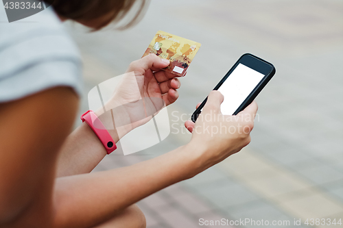 Image of Woman using phone and card for shopping