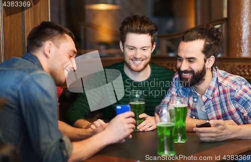 Image of friends with smartphone drinking green beer at pub