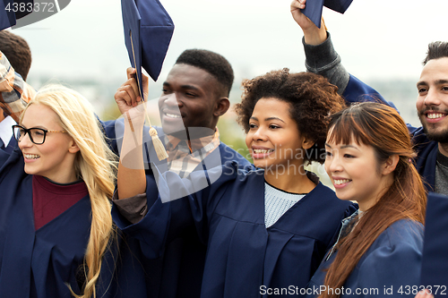 Image of happy graduates or students waving mortar boards