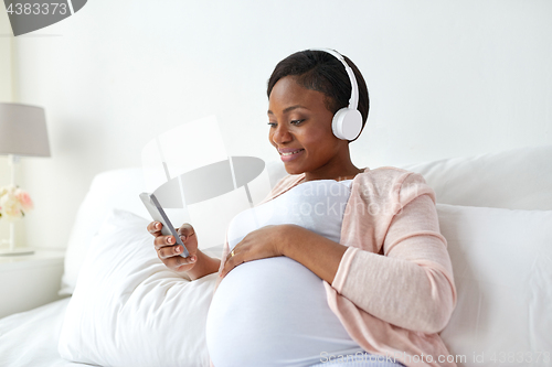 Image of pregnant woman in headphones with smartphone