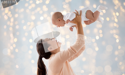 Image of happy mother playing with little baby over lights