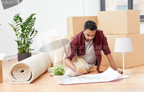 Image of man with blueprint and boxes moving to new home