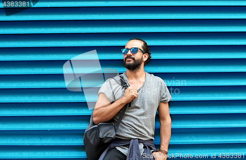 Image of man in sunglasses with bag standing at street wall