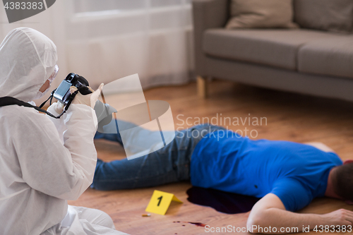 Image of criminalist photographing dead body at crime scene