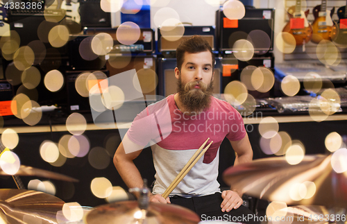 Image of male musician with cymbals at music store