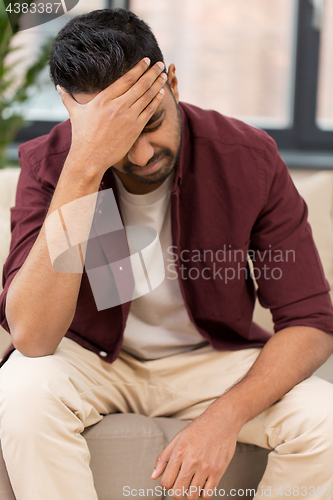 Image of unhappy man suffering from head ache at home