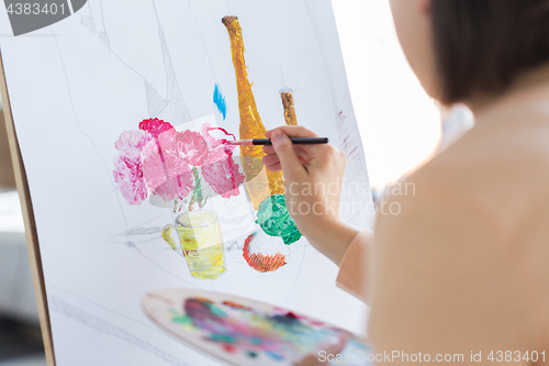 Image of artist with brush painting still life at studio