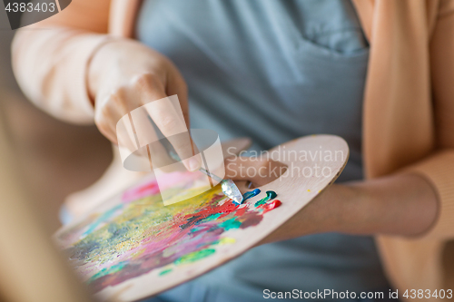 Image of artist with palette knife painting at art studio