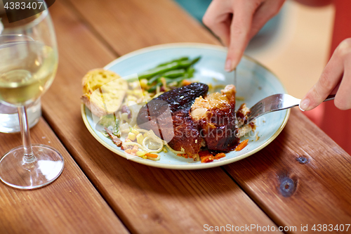 Image of hands of woman with fork eating roast chicken