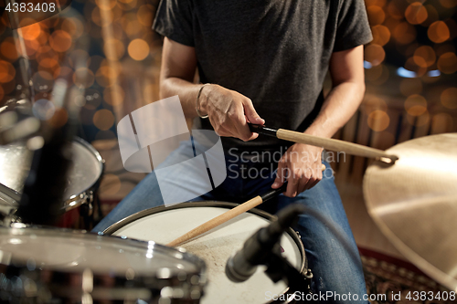 Image of musician playing drum kit at concert over lights