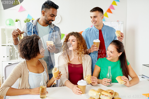 Image of happy friends or team eating at office party
