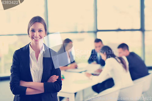 Image of business woman with her staff in background at office