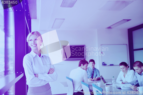 Image of business woman with her staff in background at office