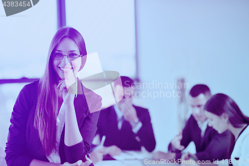 Image of business woman with her staff in background at office