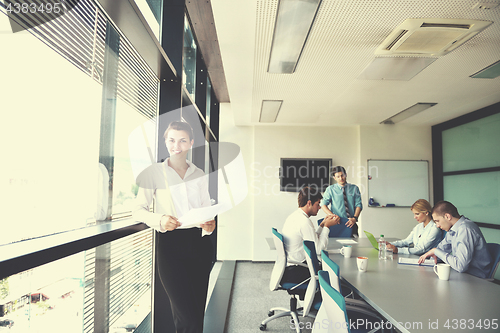 Image of business woman with her staff in background at office