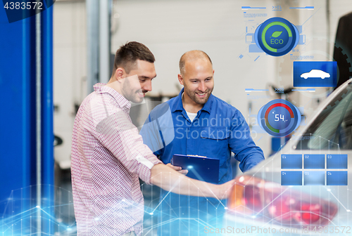 Image of auto mechanic with clipboard and man at car shop