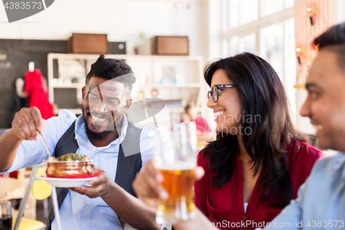 Image of happy friends eating at restaurant
