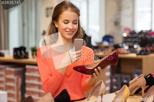 Image of woman taking photo by smartphone at shoe store