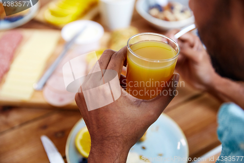 Image of close up of male hand with glass of orange juice