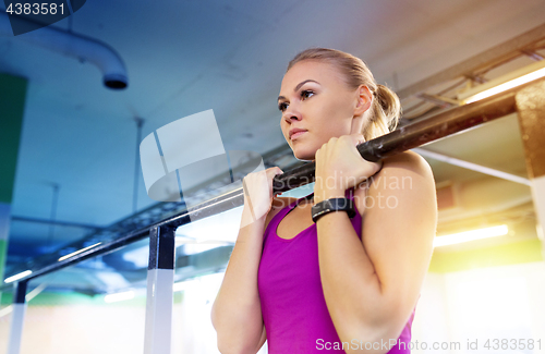 Image of woman exercising and doing pull-ups in gym