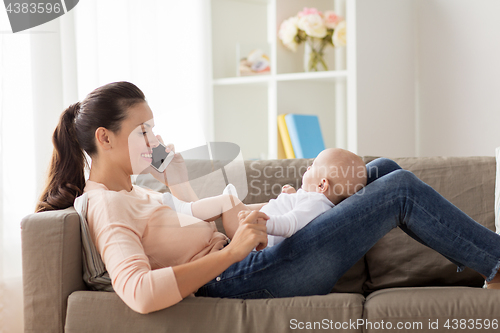 Image of mother with baby calling on smartphone at home