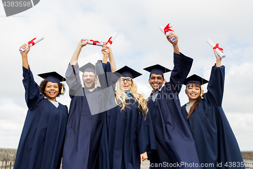 Image of happy students in mortar boards with diplomas