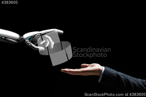 Image of robot and human hand on black background