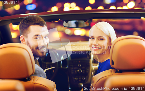 Image of happy couple sitting in car at auto show or salon