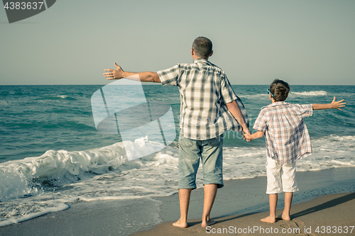 Image of Father and son playing on the beach at the day time.