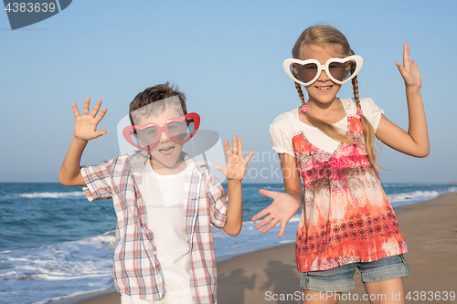 Image of Two happy little children playing on the beach at the day time. 