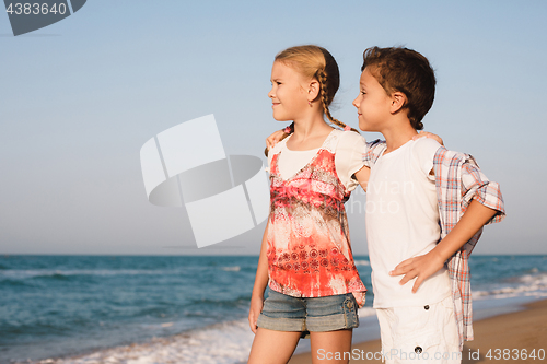 Image of Two happy little children playing on the beach at the day time.