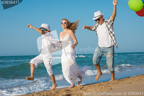 Image of Father mother and  son  playing on the beach at the day time.