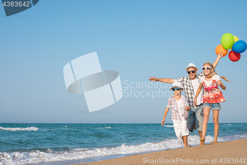 Image of Father and son and daughter playing on the beach at the day time